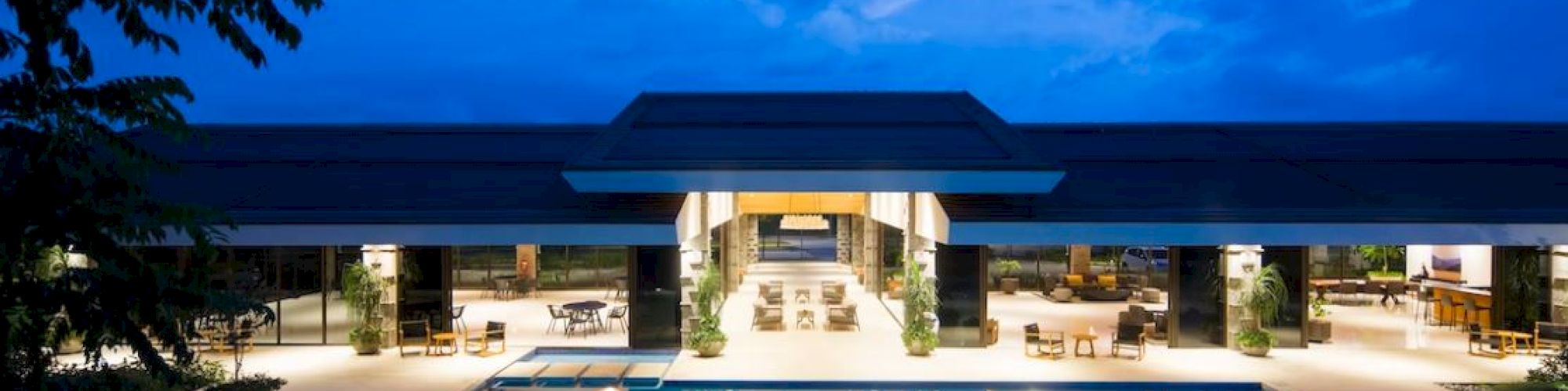 A luxurious building with an illuminated pool and seating area under a night sky creates a tranquil, inviting atmosphere.