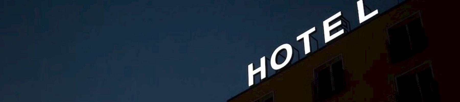 The image shows a building at night with the word "HOTEL" lit up on top, against a dark sky. The letter "L" is separated slightly.