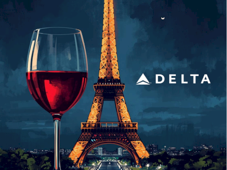 A glass of red wine with the Eiffel Tower in the background and the Delta logo beside it.