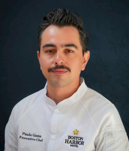 A portrait of a male executive chef in a white jacket labeled &ldquo;Paolo Garma, Executive Chef&rdquo; for the &ldquo;Boston Harbor Hotel.&rdquo;