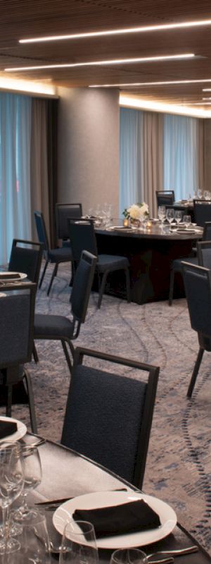 The image shows a banquet hall with round tables set for an event, featuring elegant table settings and decorative centerpieces.
